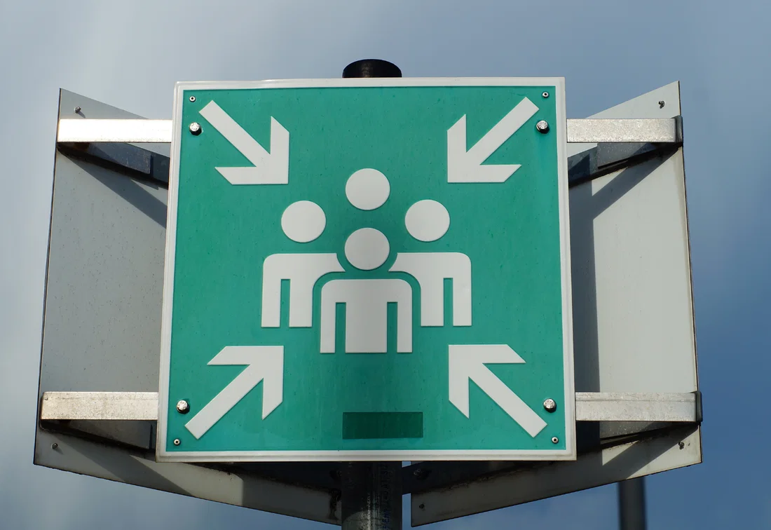 Green sign marking the assembly point for an evacuation.
