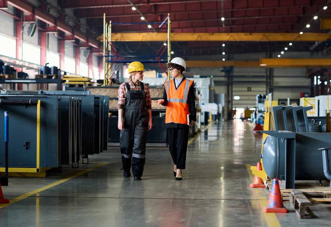 An HSE officer and an employee carrying out a safety walk in an industrial workplace.