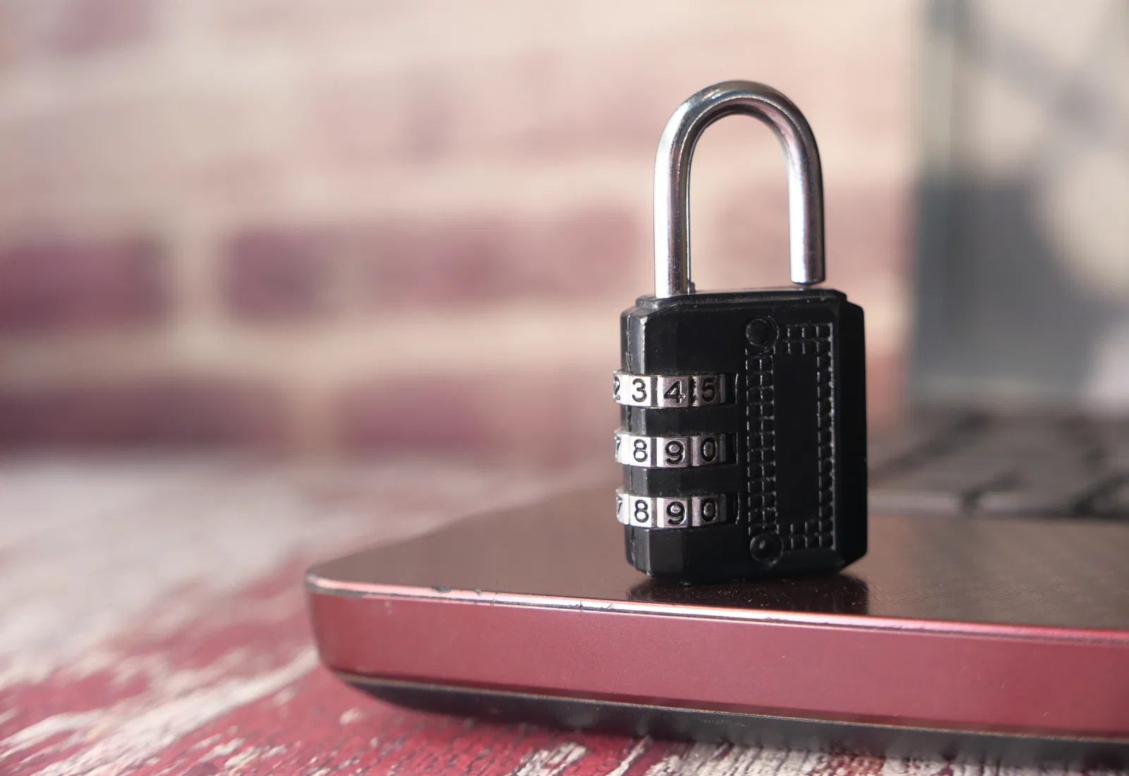 El candado de combinación negro está sobre un portátil cerrado, símbolo de una fuerte seguridad digital y física.