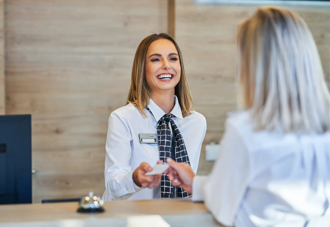 Recepcionista ajudando um visitante com atenção pessoal em um ambiente de escritório moderno.