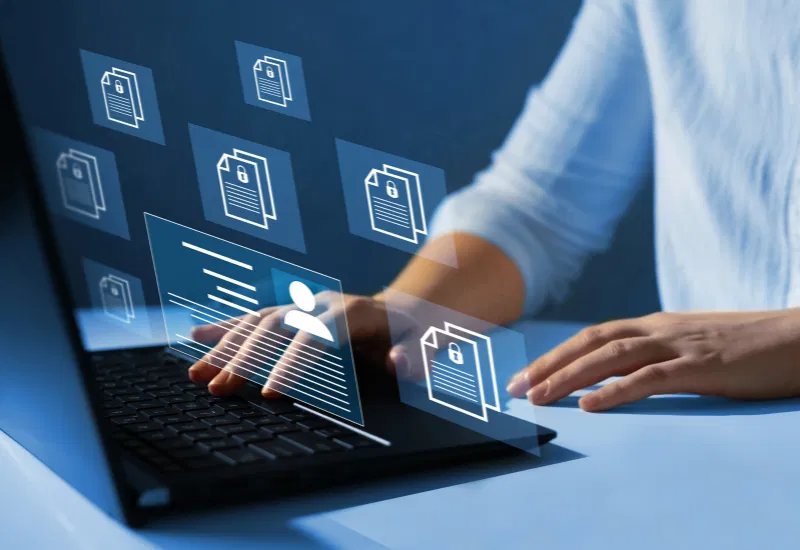 Security manager working on a laptop, overseeing digital documents and security profiles, highlighting the use of technology in modern security management.